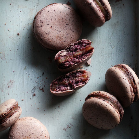 8 Blueberry Macarons on a counter.